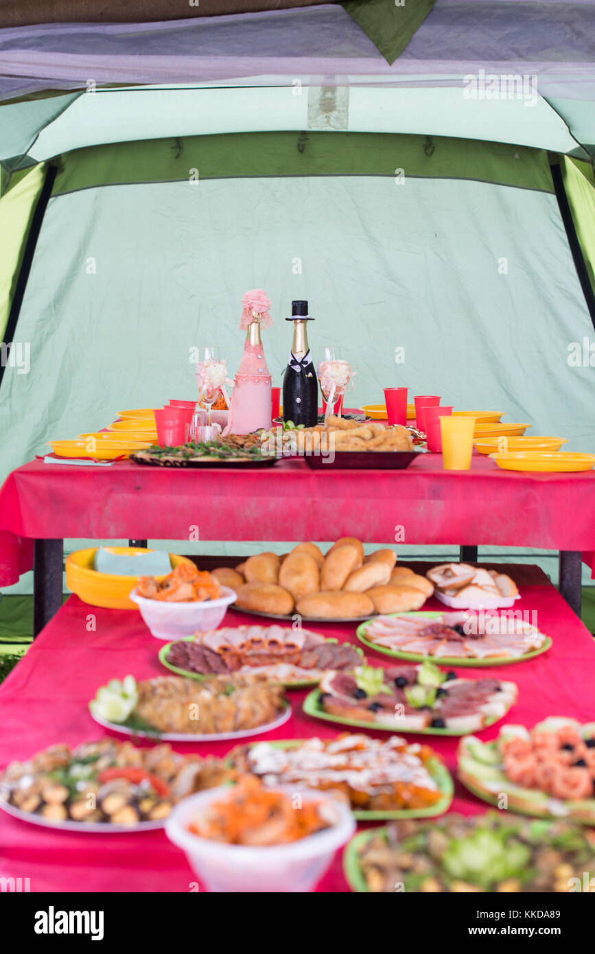 Hochzeit im Freien Tisch mit verschiedenen Gerichten auf ihn mit zwei Flaschen Champagner wunderschön dekoriert wie Braut und Bräutigam in der IT-Leiter. Stockfoto