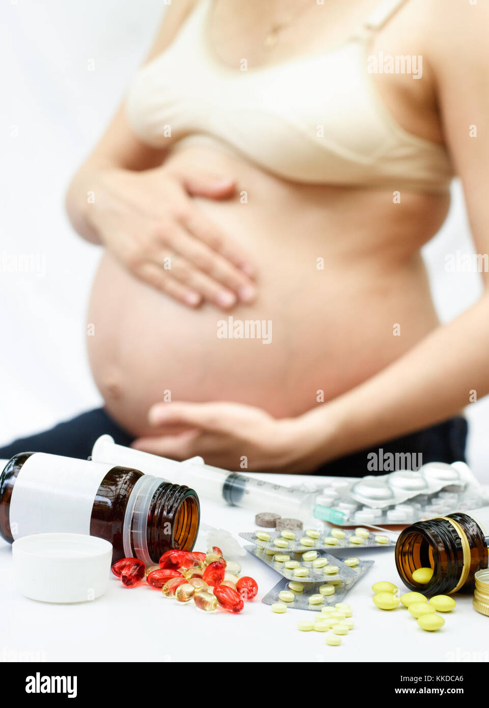 Gelbe und rote Pillen Verschütten von Flaschen und blasen vor der schwangeren Frau, flacher dof Stockfoto