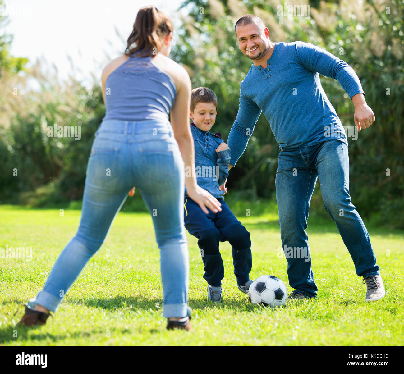 Portrait von aktiven Happy positive Familie Fußball spielen mit Sohn im Freien Stockfoto