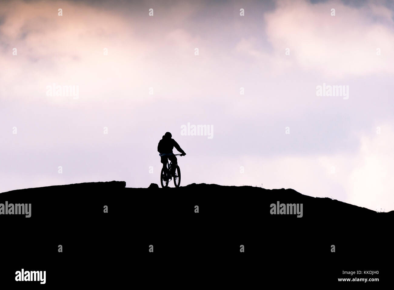 Mountainbiken - die Silhouette eines Mountainbikers, der zum Gipfel des East Pentire Newquay Cornwall UK radelt. Stockfoto