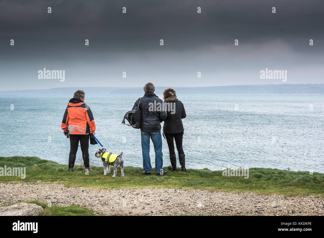 Wetter in Großbritannien - Menschen stehen auf Klippen über dem Meer, während dunkle Regenwolken sich Newquay Cornwall Großbritannien nähern. Stockfoto