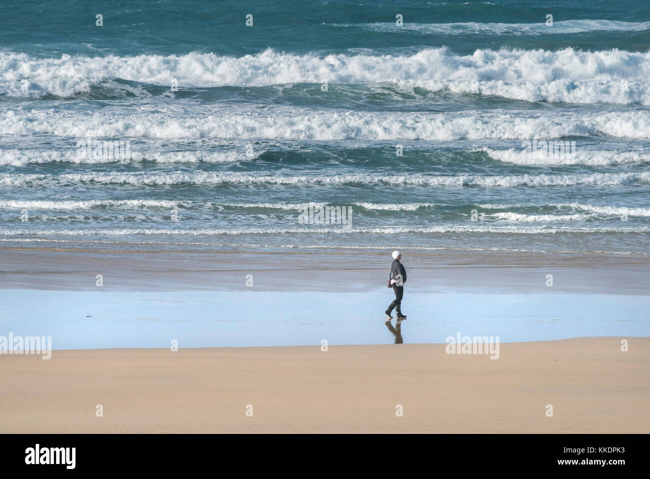 Eine Frau, die am Ufer des Fistral Beach Newquay Cornwall UK entlang läuft. Stockfoto
