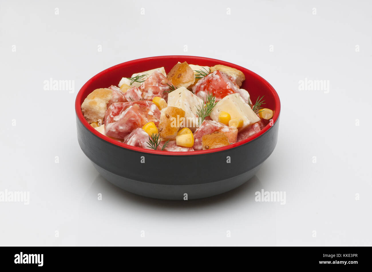 Salat mit Käse und Tomaten in einer tiefen Schwarz Cup auf weißem Hintergrund Stockfoto