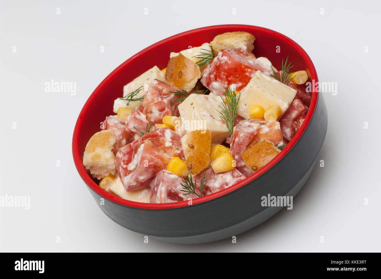 Salat mit Käse und Tomaten in einer tiefen Schwarz Cup auf weißem Hintergrund Stockfoto