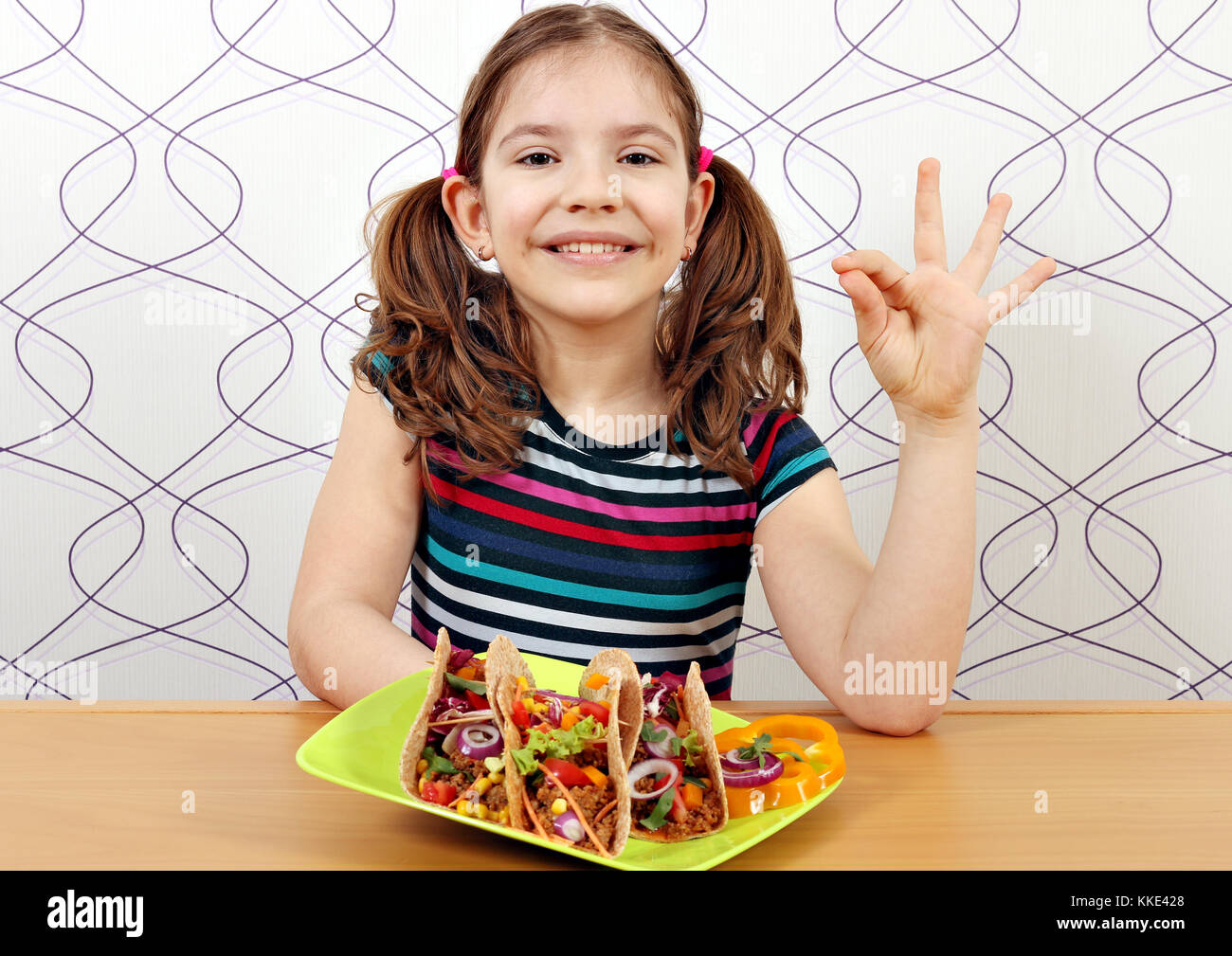 Glückliche kleine Mädchen mit Tacos und ok Handzeichen Stockfoto