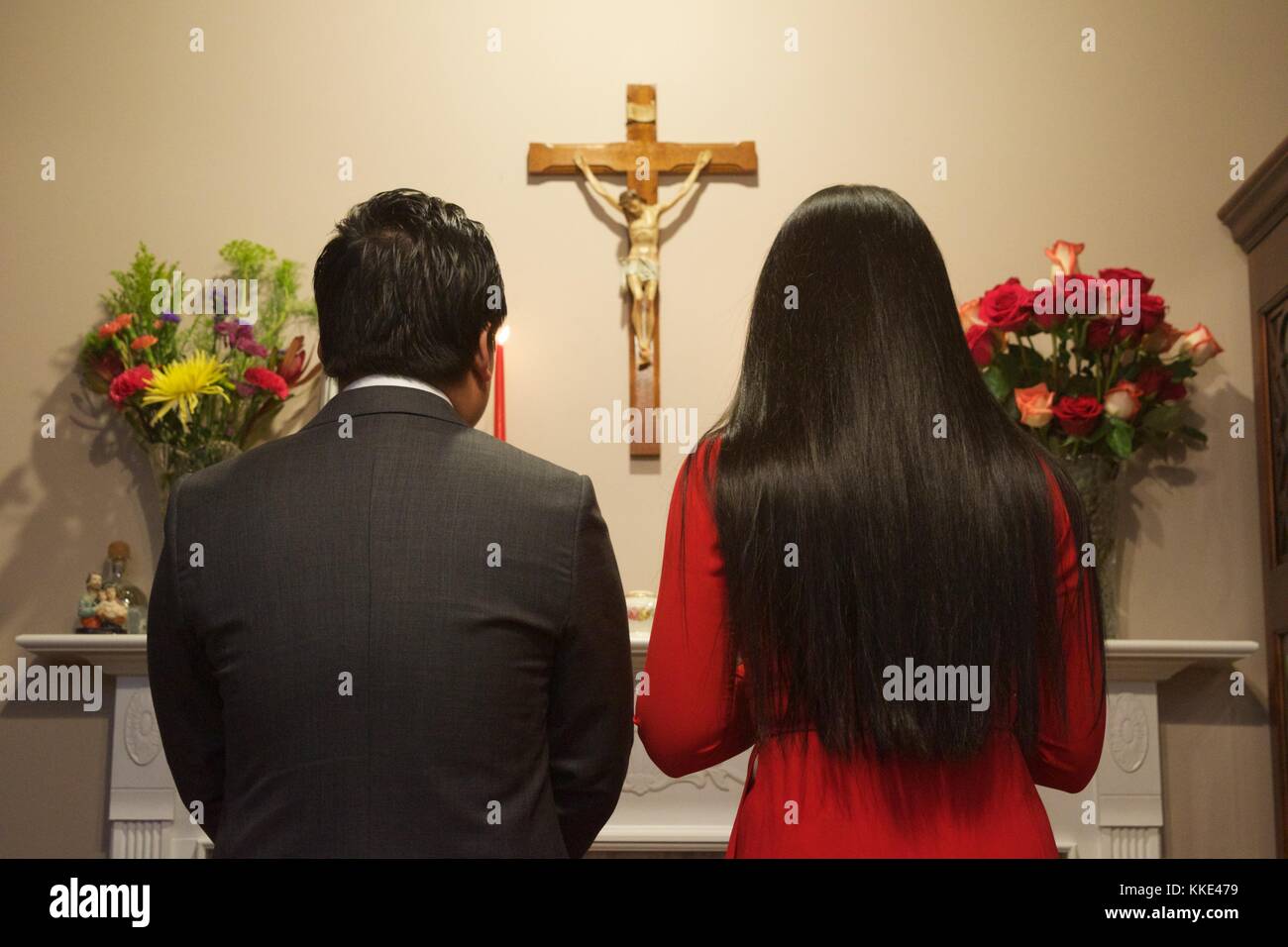 Paar steht am Altar vor einem Kruzifix während der Zeremonie Stockfoto