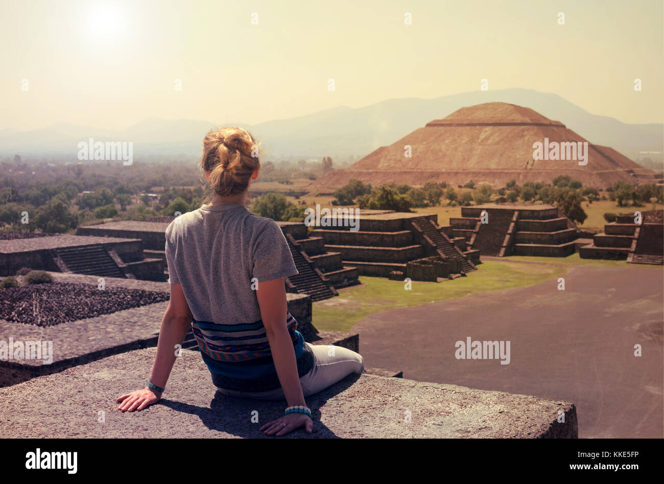 Junge Frau sitzt auf der Spitze der Pyramide mit Blick auf Teotihuacan an einem sonnigen Tag Stockfoto
