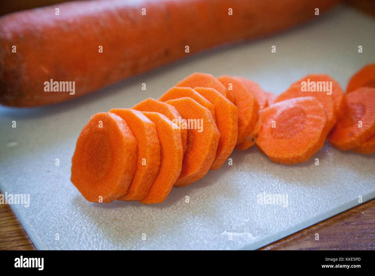 Blick von oben auf frisch gehackte OrangenKarotten auf einem Schneidebrett, bereit zum Kochen. Gesunde Lebensmittelzubereitung, Mahlzeit Vorbereitung, und Rezept Tutotorials. Stockfoto