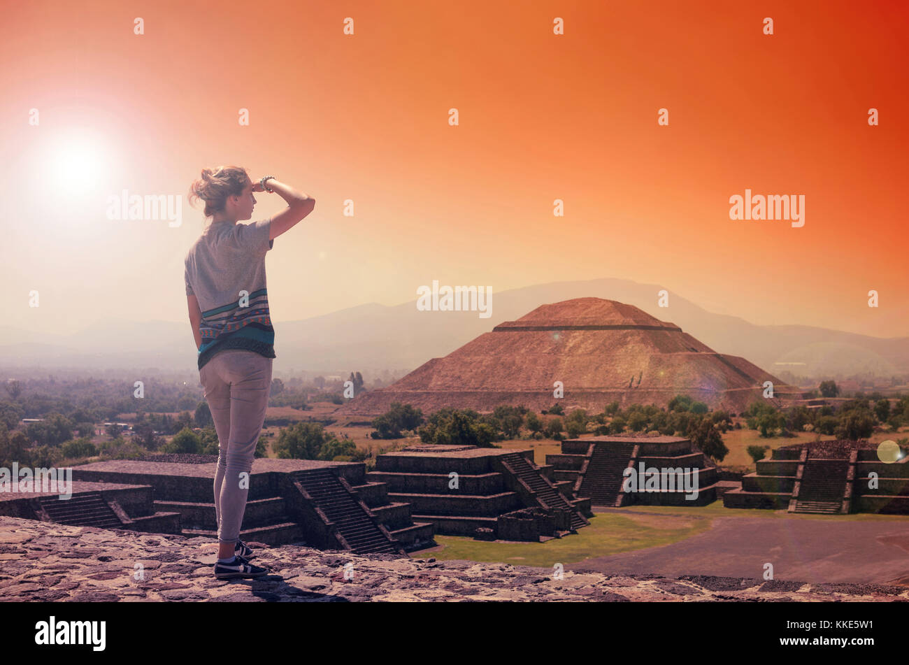 Junge Frau stand an der Spitze der Pyramide und mit Blick auf Machu Picchu in orange Sonnenuntergang Licht Stockfoto