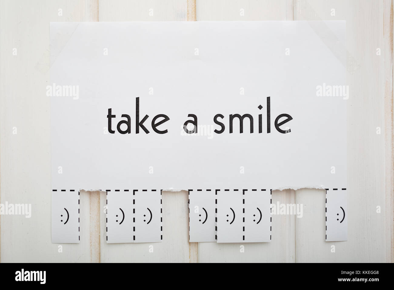Ein Papier mit den Satz: "Ein Lächeln nehmen und mit einem Lächeln Zeichen bereit zu weg zerrissen werden. Das Foto ist vorne. Stockfoto