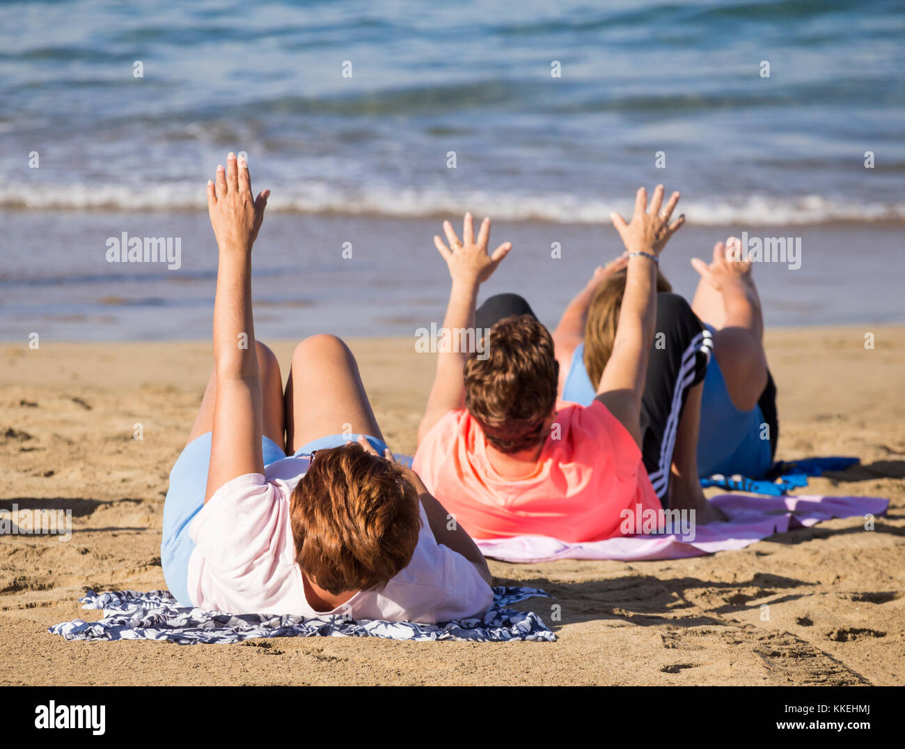 Ältere spanische Frauen dehnen sich täglich beim Yoga/Stretching am Strand. Stockfoto