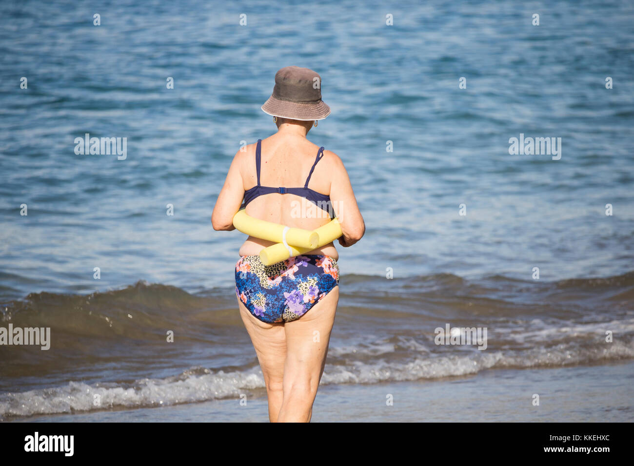 Ältere spanische Frauen, die nach ihrem täglichen Yoga-/Stretching-Kurs am Strand im Meer schwimmen gehen. Stockfoto