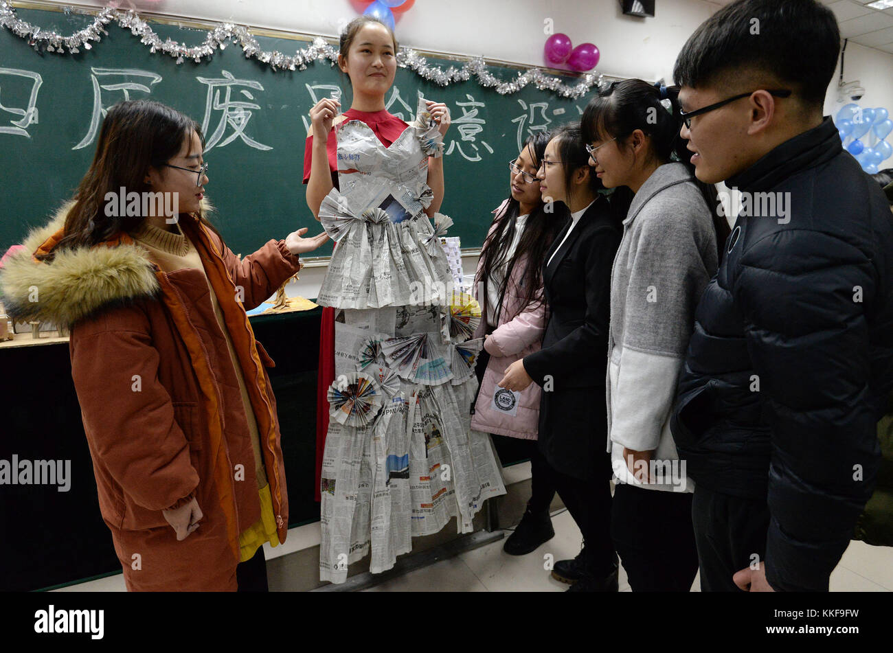 Handan, chinesische Provinz Hebei. Dezember 2017. Studenten der Hebei University of Engineering betrachten das „Hochzeitskleid“ aus Zeitungsmüll in Handan, nordchinesischer Provinz Hebei, 5. Dezember 2017. Die Universität führte einen innovativen Designwettbewerb durch, um ein umweltfreundliches Lebenskonzept zu fördern. Quelle: Hao Qunying/Xinhua/Alamy Live News Stockfoto