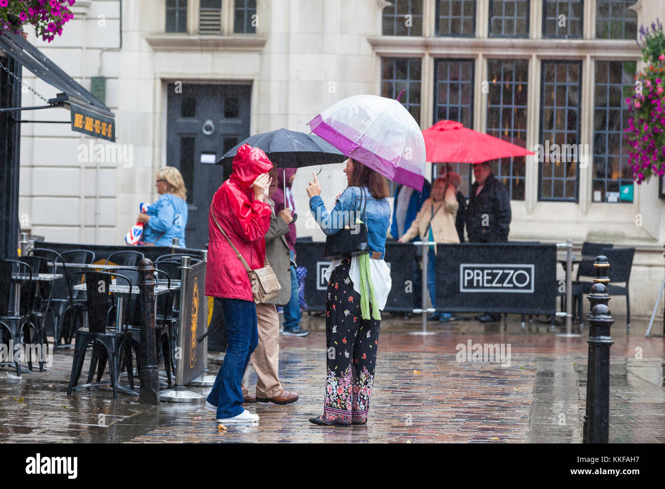 Canterbury, Kent, Großbritannien. 29. September 2017. Eine Gruppe von Damen mit Sonnenschirmen sprechen im strömenden Regen in der High Street. Stockfoto