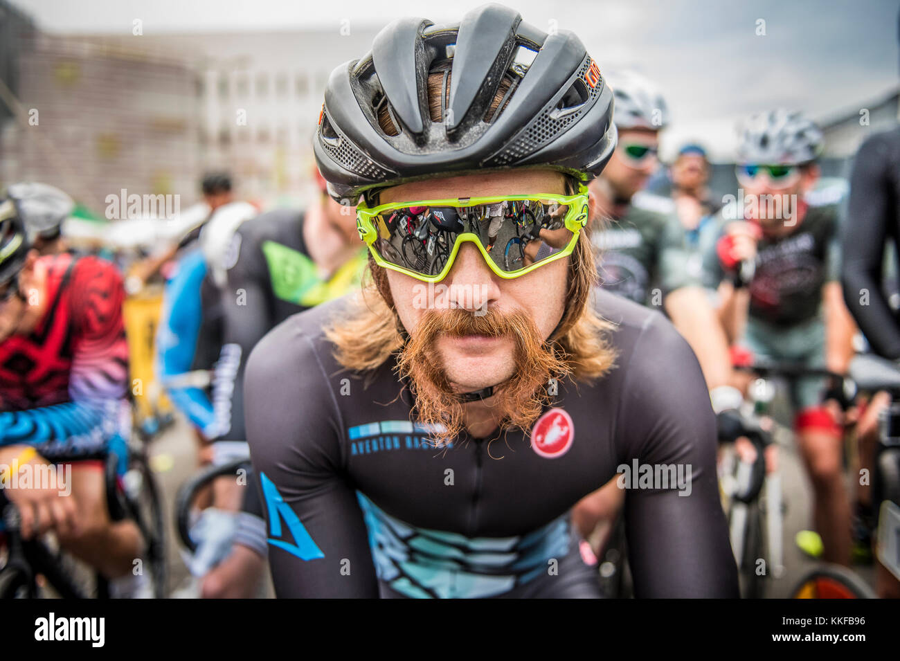 Radsportler beim Radrennen Redhook auf der Greenwich Peninsula in London, die sich mit Oakley-Kieferknochen-Sonnenbrillen und Radsportstimmung auf den Start des Rennens vorbereiten Stockfoto