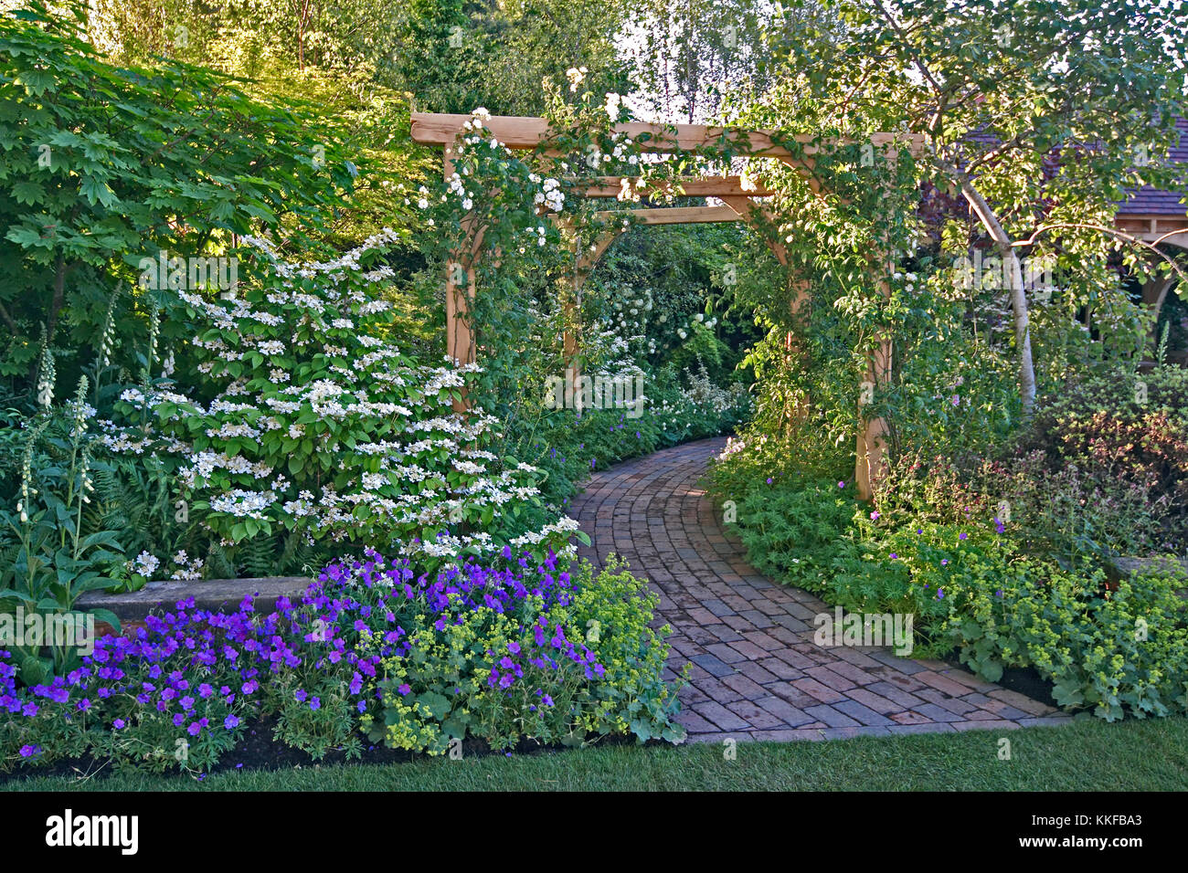 Als typisch britische traditionelle Country Garden mit gepflasterten Gehweg gestaltet Stockfoto