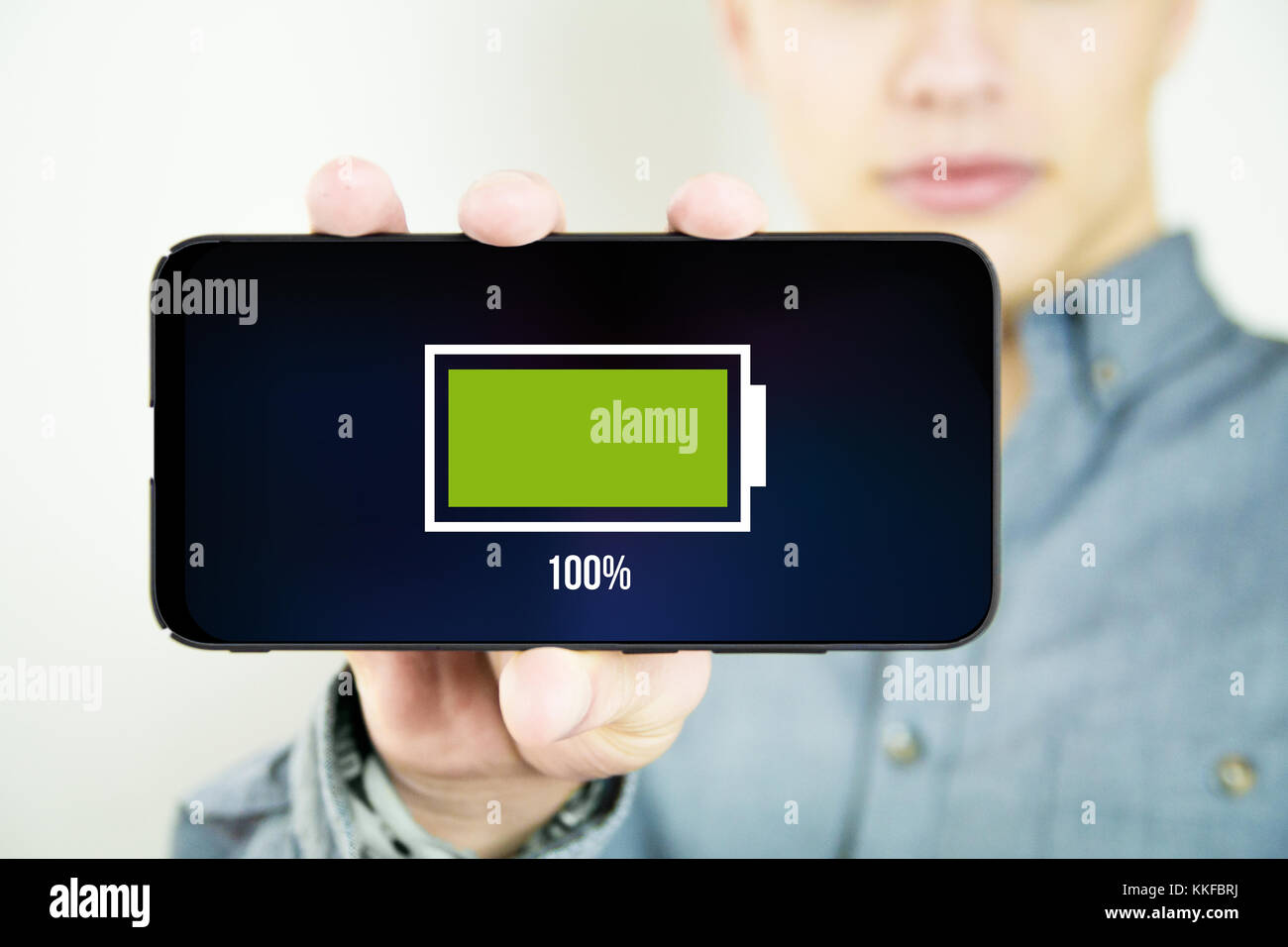 Junge Mann, und mit einem vollen Akku full screen Smartphone Stockfoto