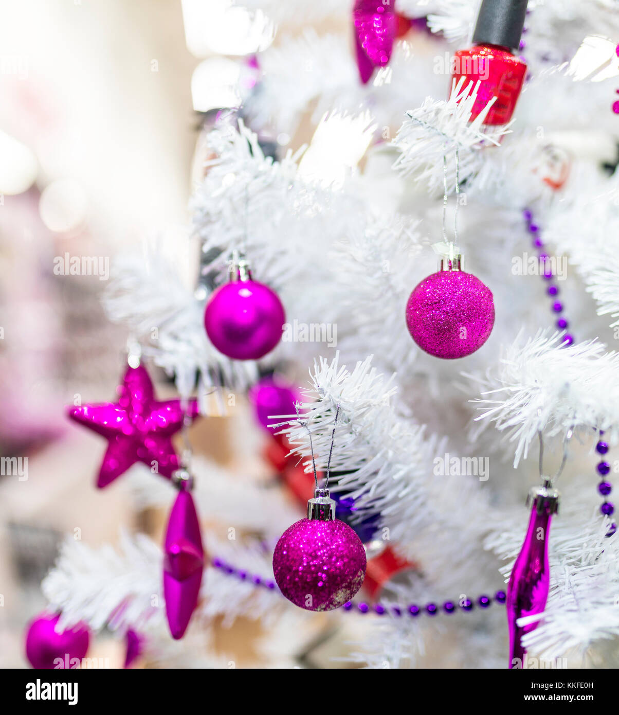 Lila Kugeln und Dekorationen hängen an einem weißen Weihnachtsbaum im Schaufenster einer mall