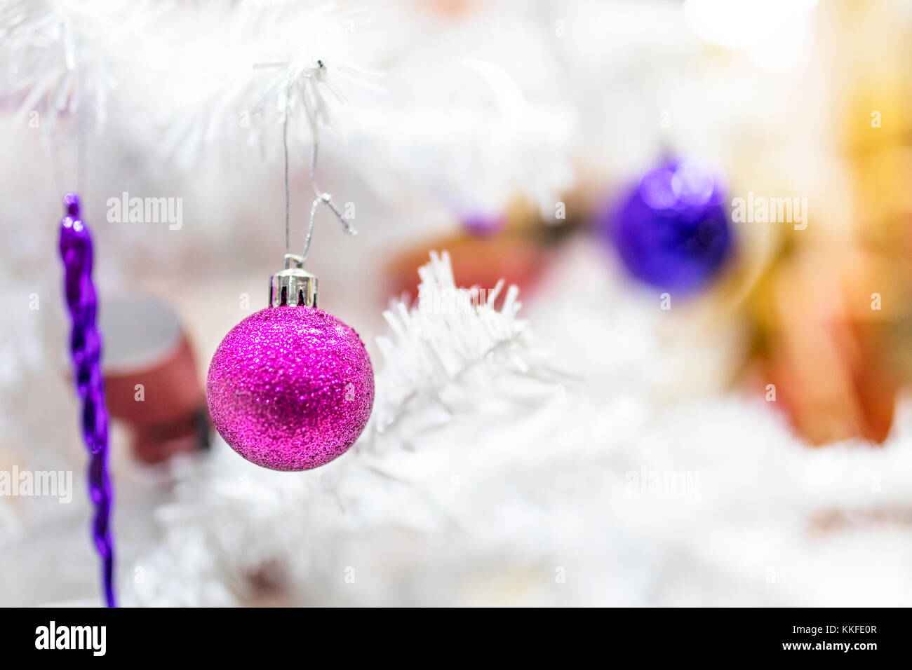 Lila Kugeln und Dekorationen hängen an einem weißen Weihnachtsbaum im Schaufenster einer mall Store in Großbritannien Stockfoto