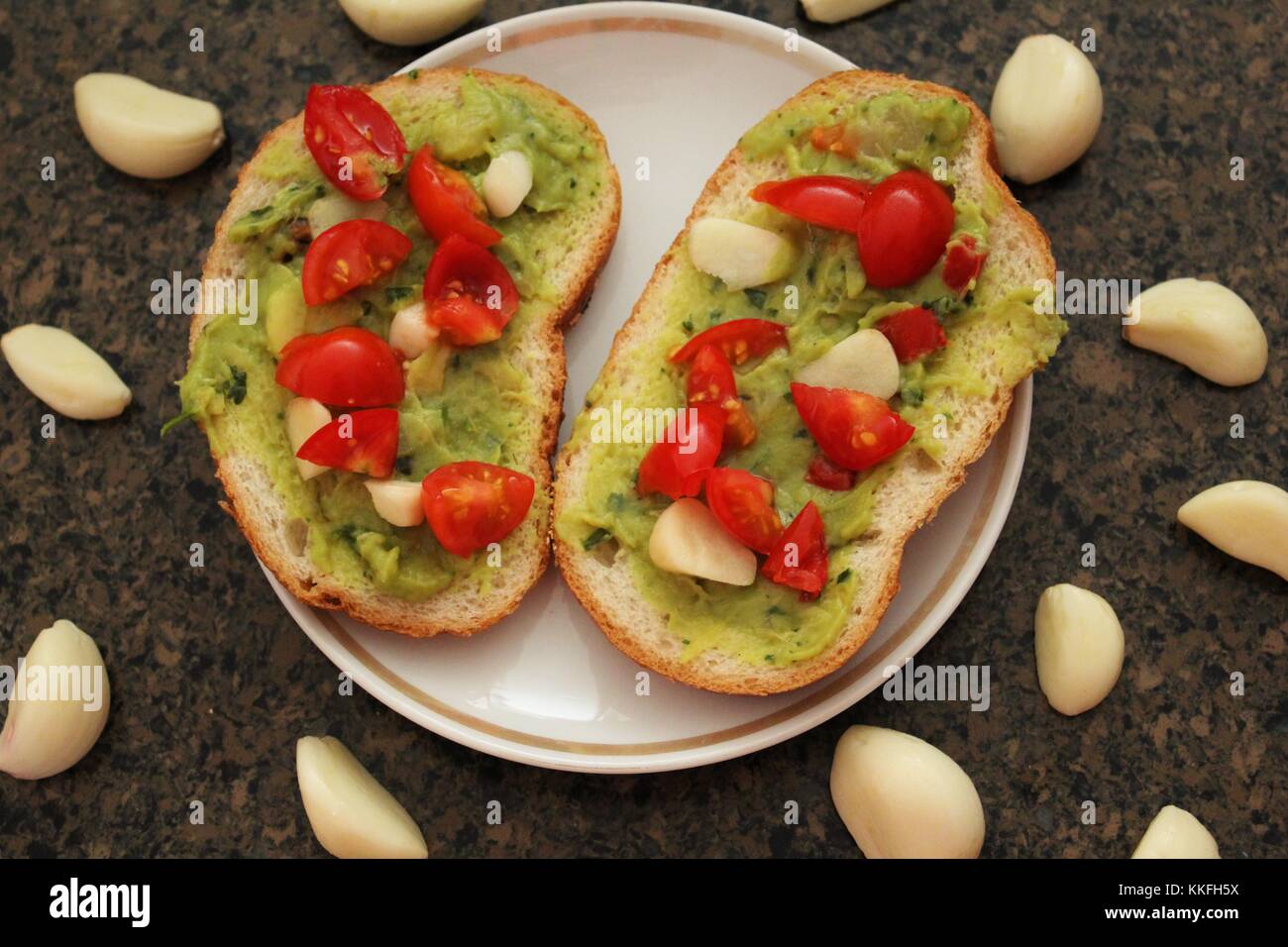 Avocado Toast mit Tomaten und Knoblauch. Stockfoto