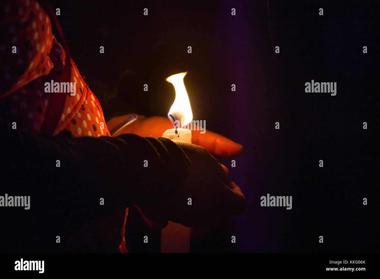 Ein mexikanischer Pilger woman holding mit beiden Händen eine brennende Kerze in der Nacht Stockfoto