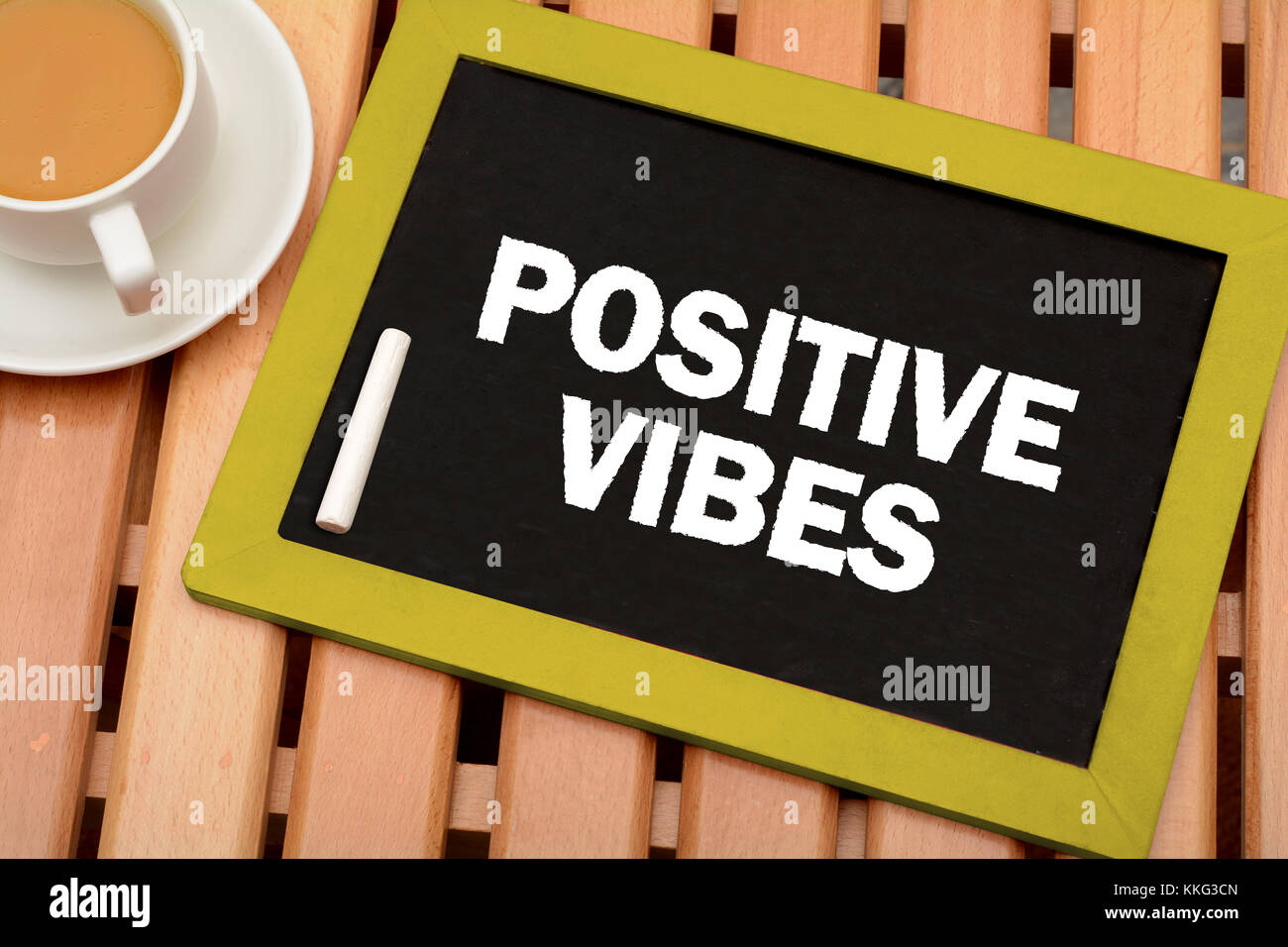 Positive Vibes Nachricht auf Schiefertafel mit Tasse Tee Stockfoto