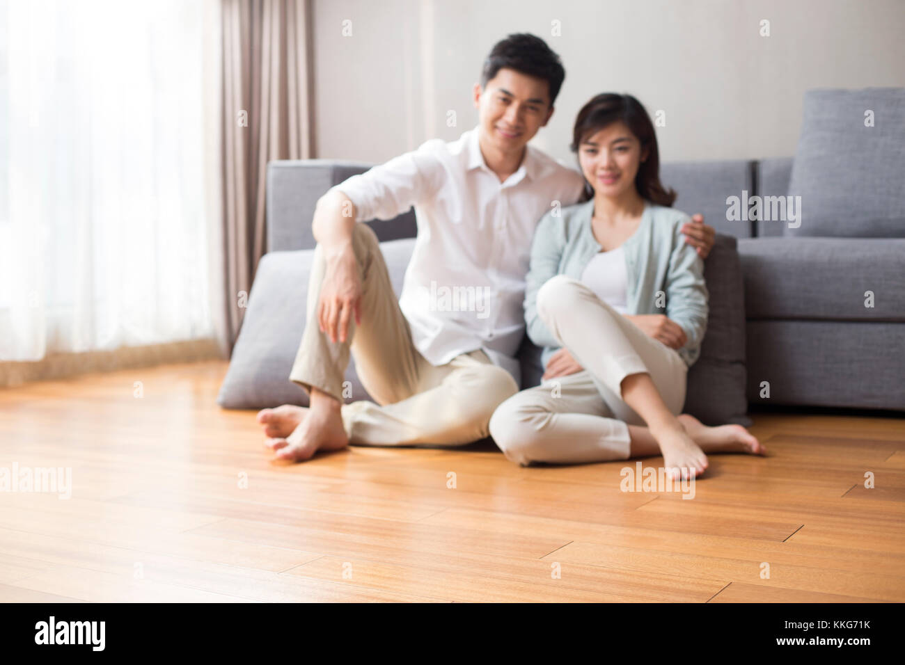 Glückliche junge chinesische Paare sitzen auf Holzboden Stockfoto