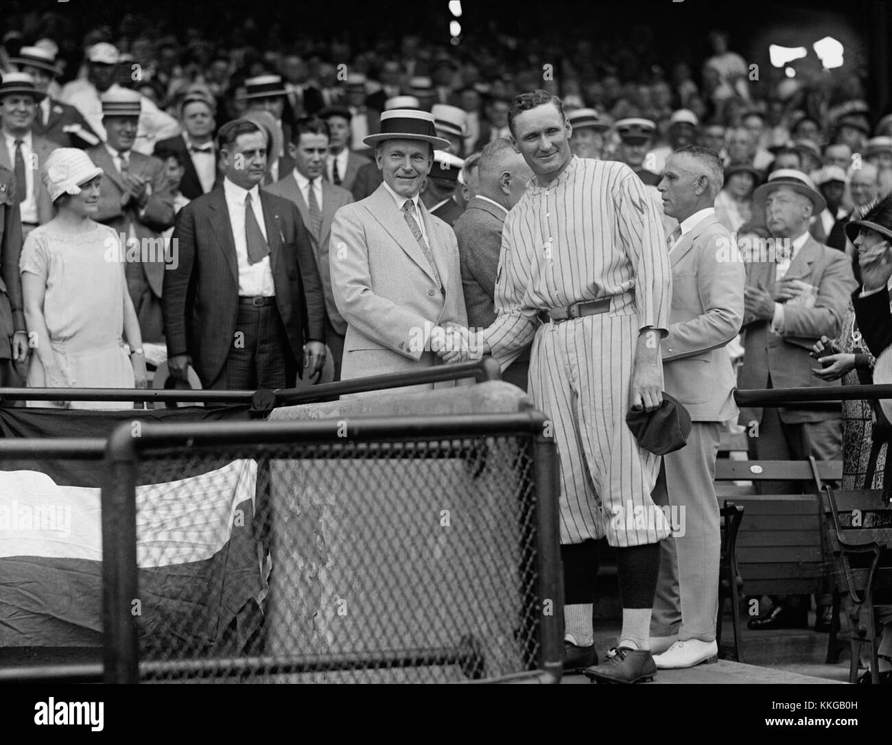 Walter Johnson, ein bekannter Baseballkrug, wird in diesem Moment mit Calvin Coolidge, dem 30. Präsidenten der Vereinigten Staaten, gefangen genommen. Das historische Foto zeigt eine bemerkenswerte Interaktion zwischen einem legendären Sportler und einem US-Präsidenten. Stockfoto
