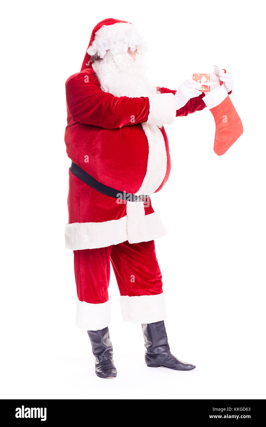 Weihnachtsmann versteckt Geschenk im Strumpf Stockfoto