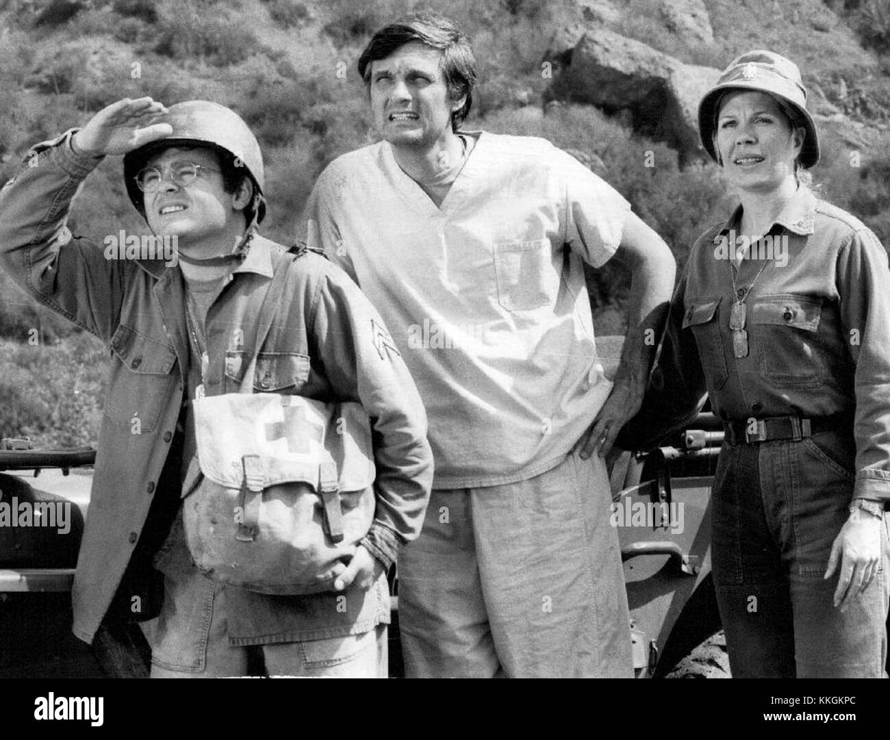 Ein Werbebild mit Gary Burghoff, Alan Alda und Loretta Swit aus der legendären TV-Serie *M*A*S*H* (1977). Das Trio repräsentiert Schlüsselfiguren aus der populären Militär-Comedy-Drama-Serie, die für ihre Mischung aus Humor und sozialen Kommentaren bekannt ist. Stockfoto