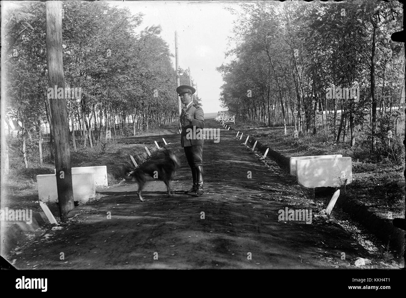 Dieses Foto zeigt einen Soldaten, der mit einem Hund auf einem Weg in einem Park spaziert, aufgenommen 2014. Es fängt einen ruhigen Moment ein, in dem Militärpersonal in einem Park mit einem Begleittier in Berührung kommt. Stockfoto