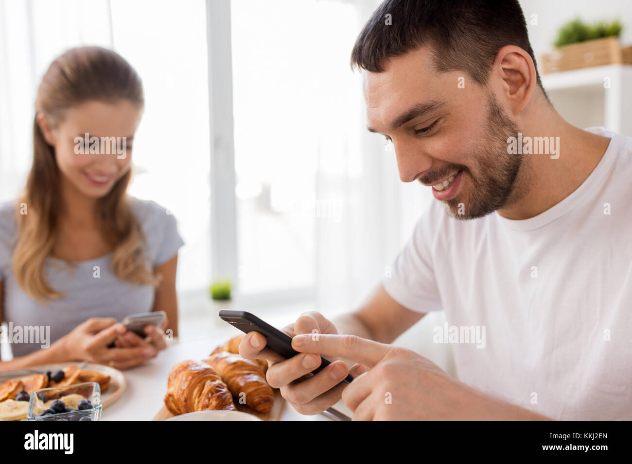Paar mit Smartphones Frühstück zu Hause in Stockfoto