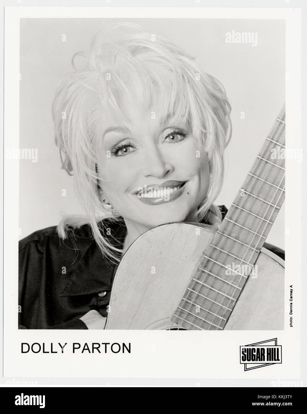 Dolly Parton, eine ikonische Figur in der Country-Musik, wird gezeigt, die ihre Gitarre hält. Parton ist bekannt für ihre kraftvollen Gesangs- und Songwriting-Fähigkeiten und hat einen großen Einfluss auf die Musikindustrie gehabt und Country-, Pop- und Bluegrass-Genres in ihre Karriere integriert. Stockfoto