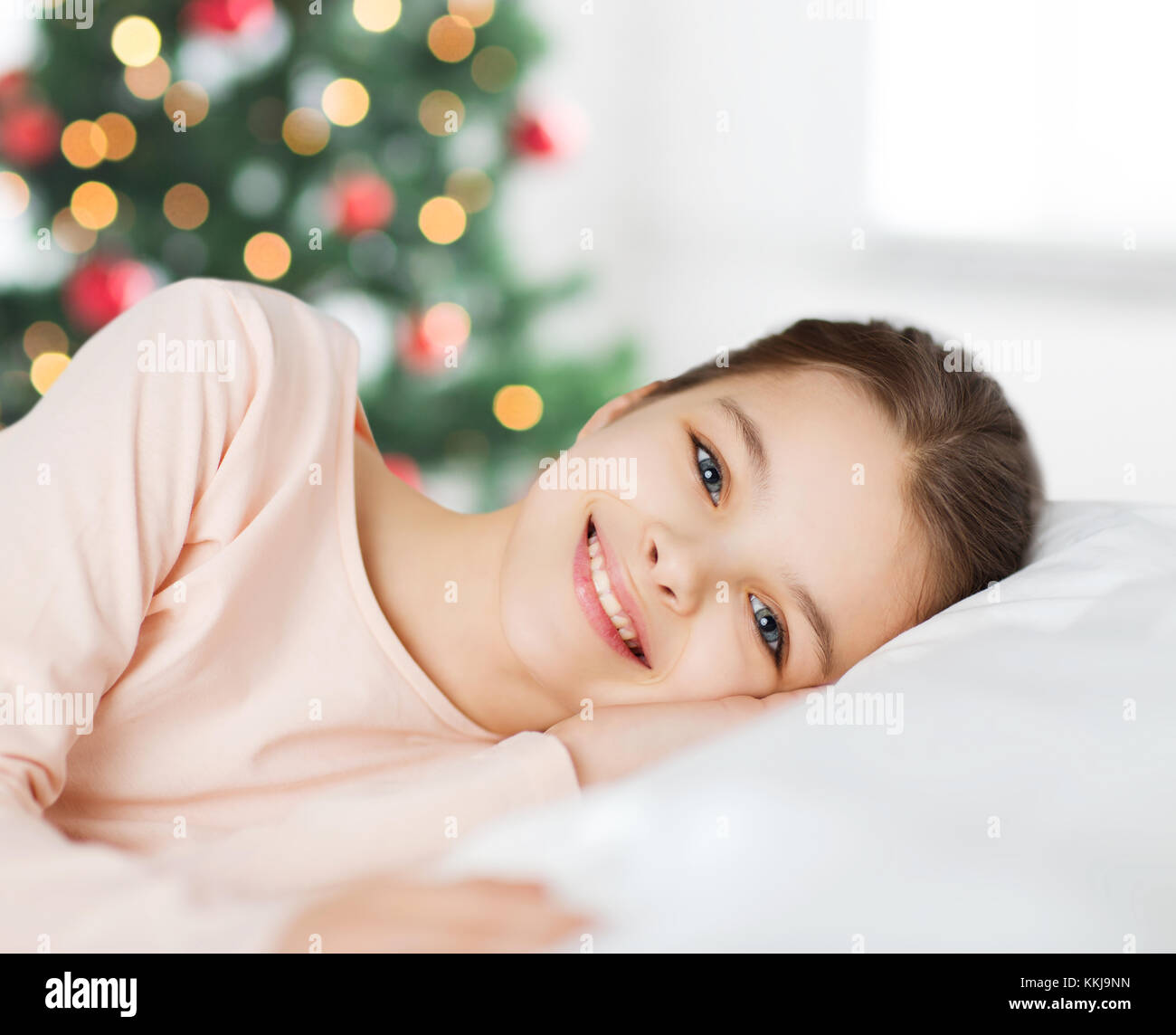 Glücklich lächelnde Mädchen liegt wach im Bett zu Weihnachten Stockfoto