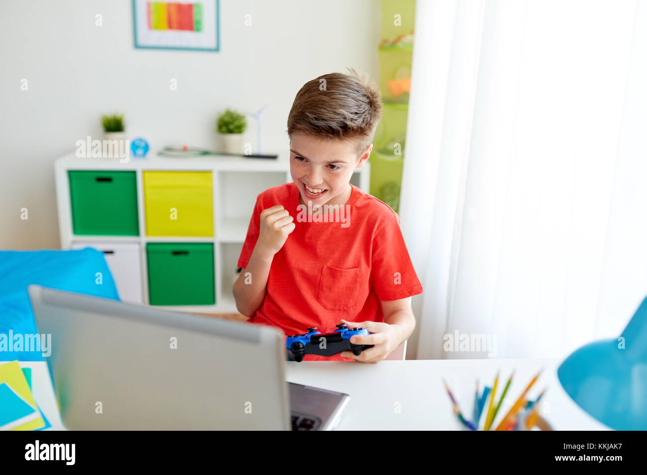 Junge mit Gamepad spielen video game auf Laptop Stockfoto