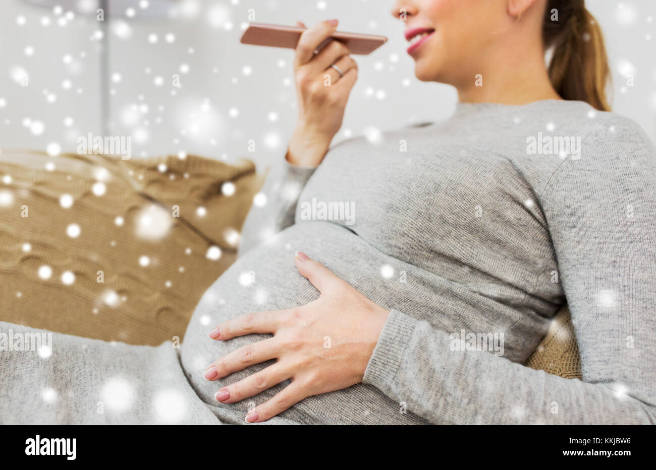 Schwangere Frau mit Voice-Recorder auf smartphone Stockfoto