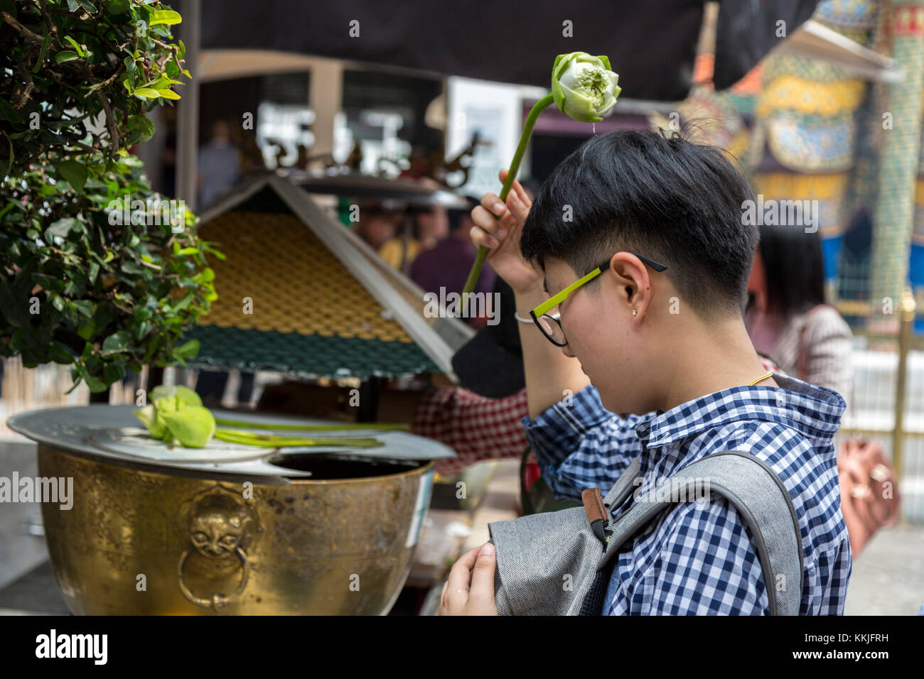 Bangkok, Thailand. Anbeter Besprengung heiliges Wasser auf dem Kopf mit einer Lotusblüte, Royal Grand Palace Compound. Stockfoto