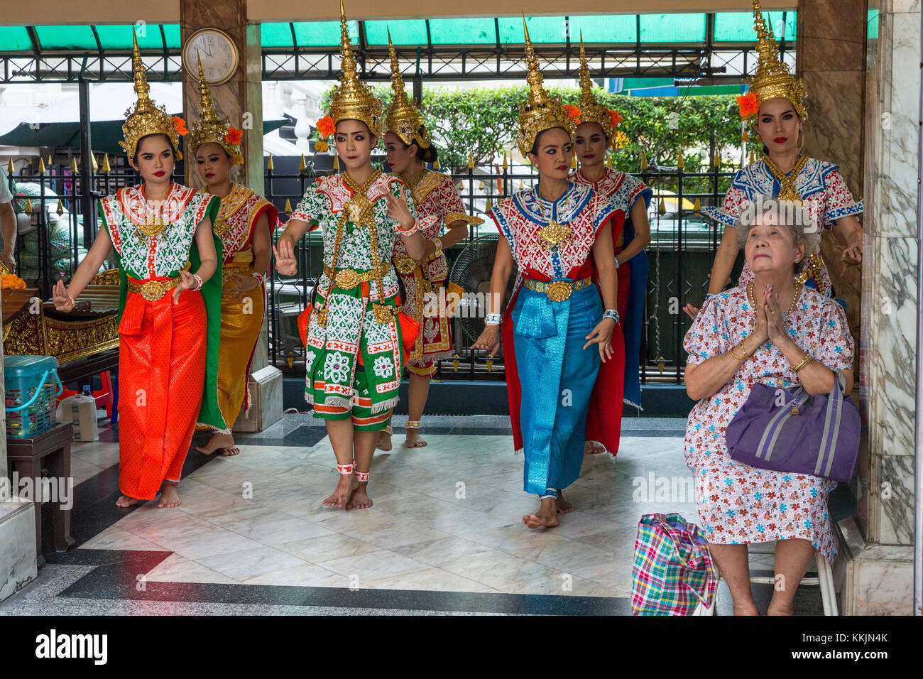 Bangkok, Thailand. Erawan Schrein. Thai Tänzer tanzen als ein Segen für Spender, der sitzt im Stuhl. Stockfoto