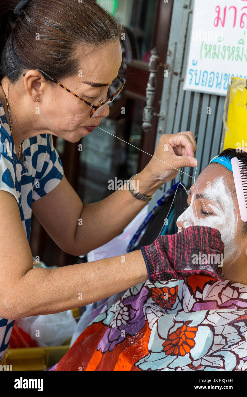 Bangkok, Thailand. Gesichtspflege Haarentfernung durch einen Praktizierenden auf der Straße in Chinatown. Stockfoto