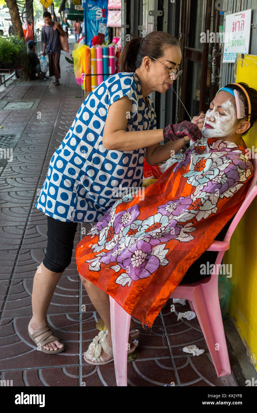 Bangkok, Thailand. Gesichtspflege Haarentfernung durch einen Praktizierenden auf der Straße in Chinatown. Stockfoto