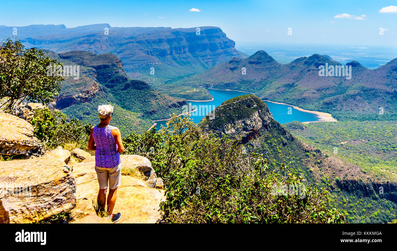 Ältere Frau, die den Blick auf den Blyde River Canyon und den Blyde River Dam vom Aussichtspunkt an den drei Rondavels in Mpumalanga, Südafrika, genießt Stockfoto