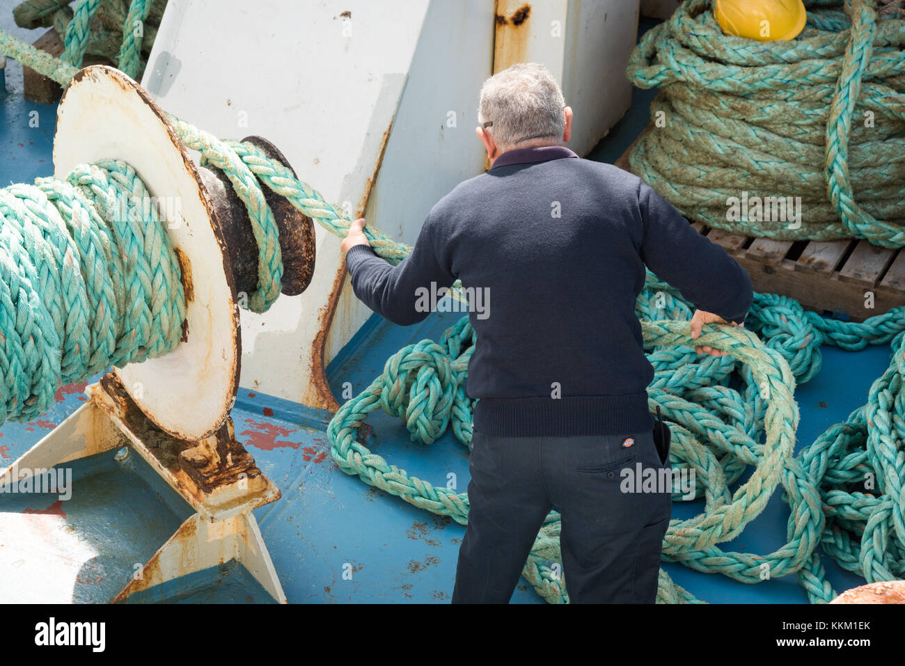 Arbeiter auf Gozo Channel Line Fähre Maschinen bedienen und wickeln Seil um eine Winde, als das Schiff den Hafen verlässt. Stockfoto