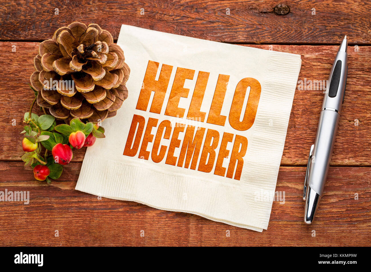 Hallo Dezember - word Abstract auf einer Serviette mit einem Pine Cone gegen die rustikale Scheune Holz Stockfoto
