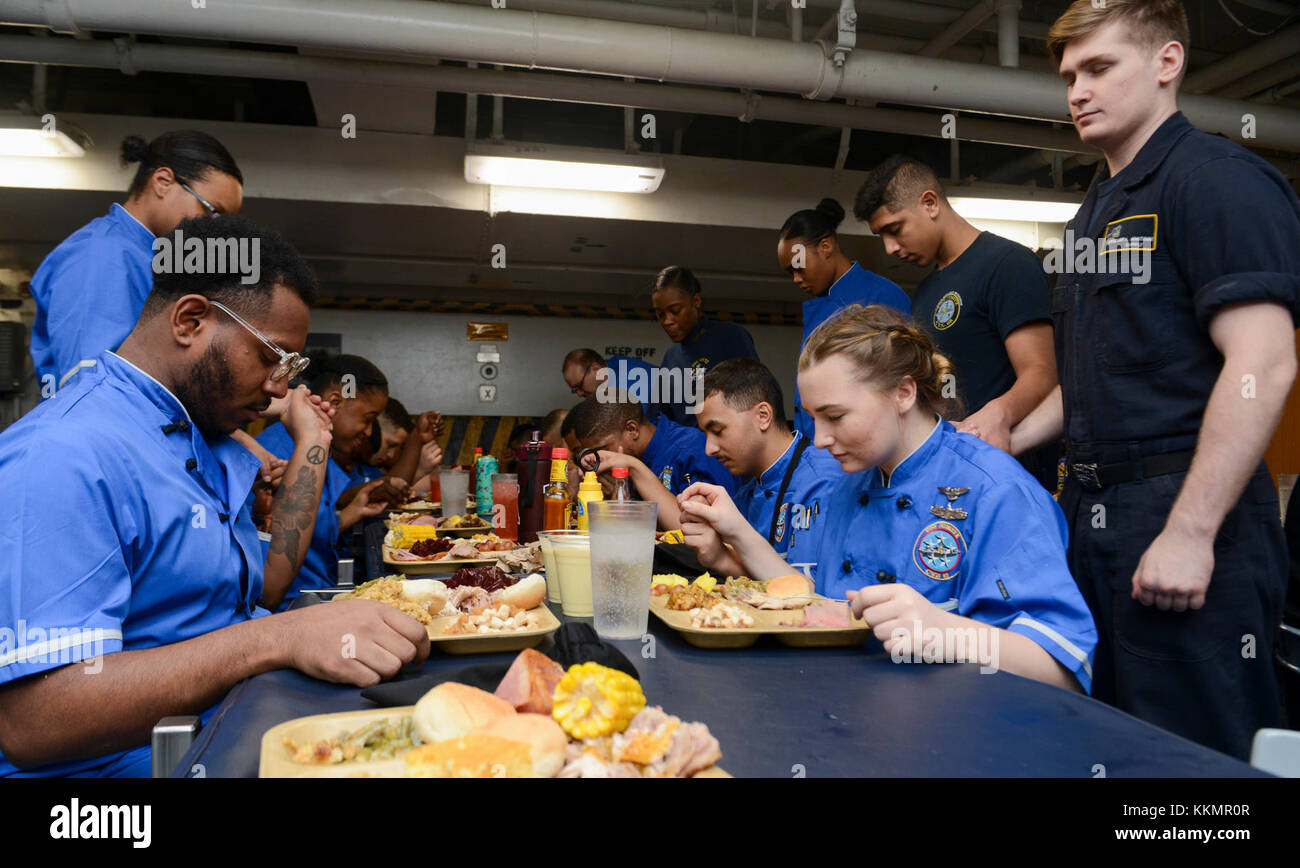 Pazifik (Nov. 23, 2017) U.S. Navy Segler nehmen Sie sich einen Moment Zeit, um Gnade vor dem Essen Thanksgiving Dinner an Bord der Flugzeugträger USS Nimitz (CVN 68), November 23, 2017, im Pazifischen Ozean zu sagen. Der Nimitz Carrier Strike Group ist auf einem regelmäßig geplanten Einsatz in den Westpazifik. Die US-Marine hat die Indo-Asia-pazifischen Region routinemäßig für mehr als 70 Jahre Frieden und Sicherheit patrouillierte. (U.S. Marine Foto von Mass Communication Specialist Seaman Jose Madrigal) Stockfoto