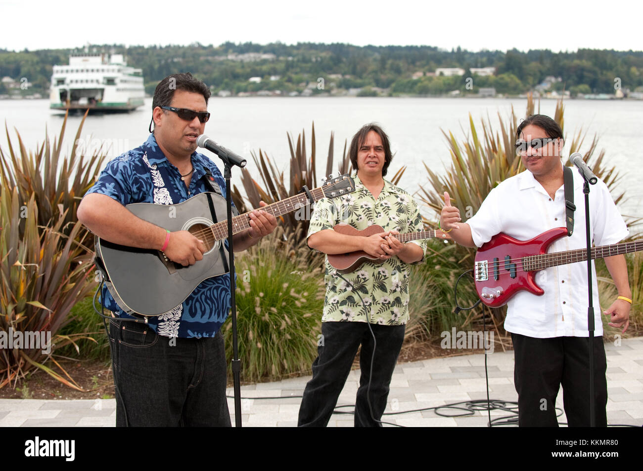 Drei Musiker im Hawaiianischen Stil der outdoor Park in der Nähe der Fähranlegestelle am Meer Stockfoto