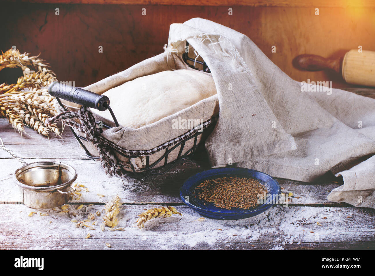 Brot backen. Teig in proofing Warenkorb auf hölzernen Tisch mit Mehl, Kümmel und Weizen Ohren. In retro Filter Effekt Stockfoto