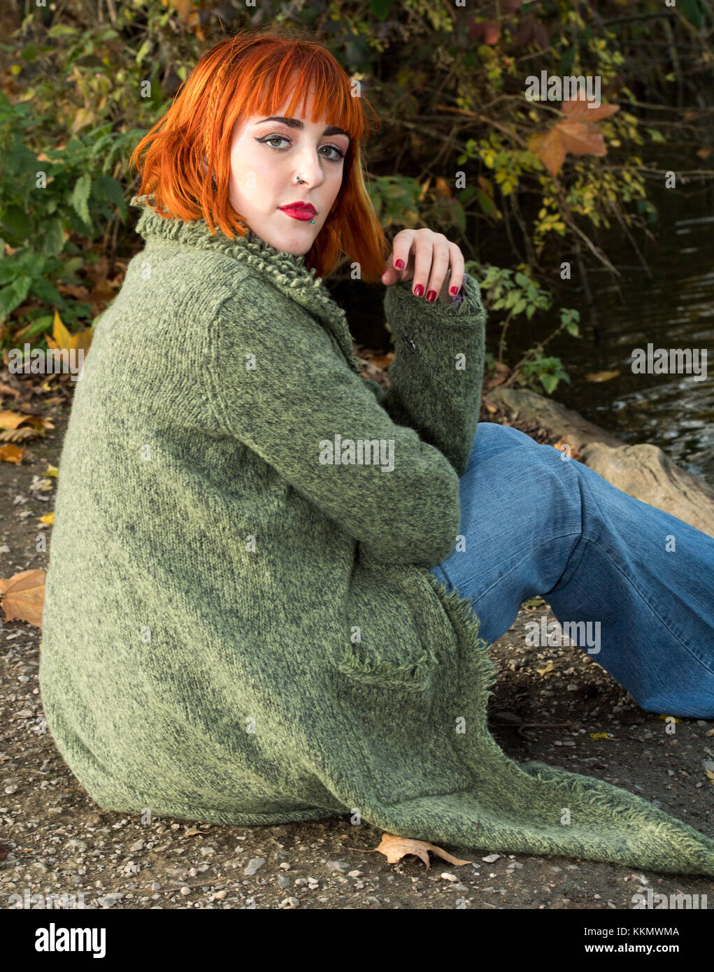 Schöne rothaarige Mädchen im Park neben dem See im Herbst Stockfoto