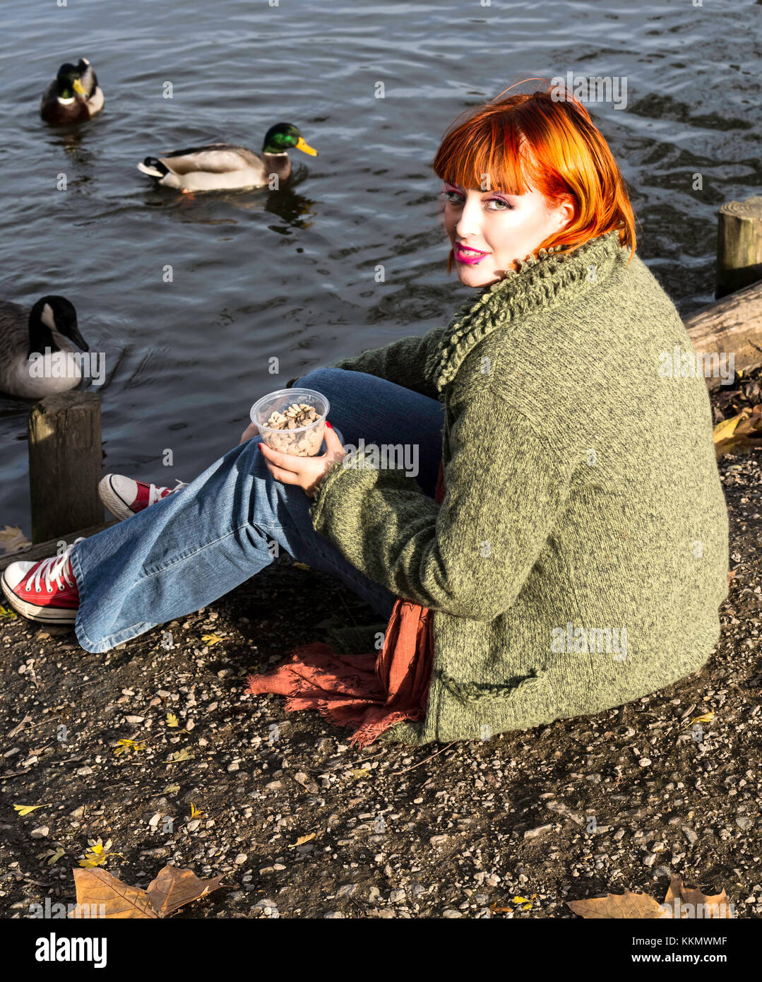 Schöne Mädchen im Park feeding ducks im Herbst Stockfoto