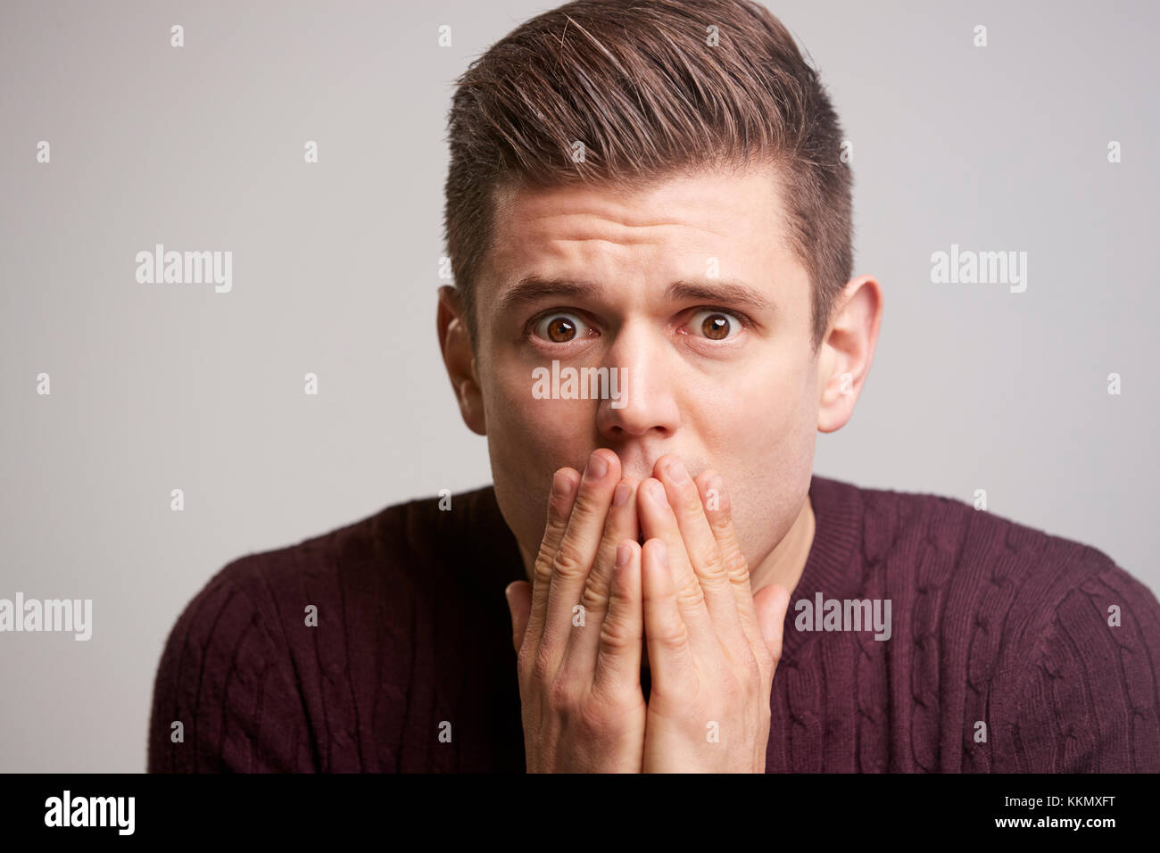 Close up Portrait von einem erschrockenen jungen Mann mit Händen zu Gesicht Stockfoto