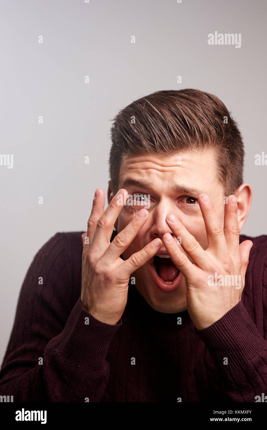Junge weiße Mann durch seine Finger suchen Angst Stockfoto
